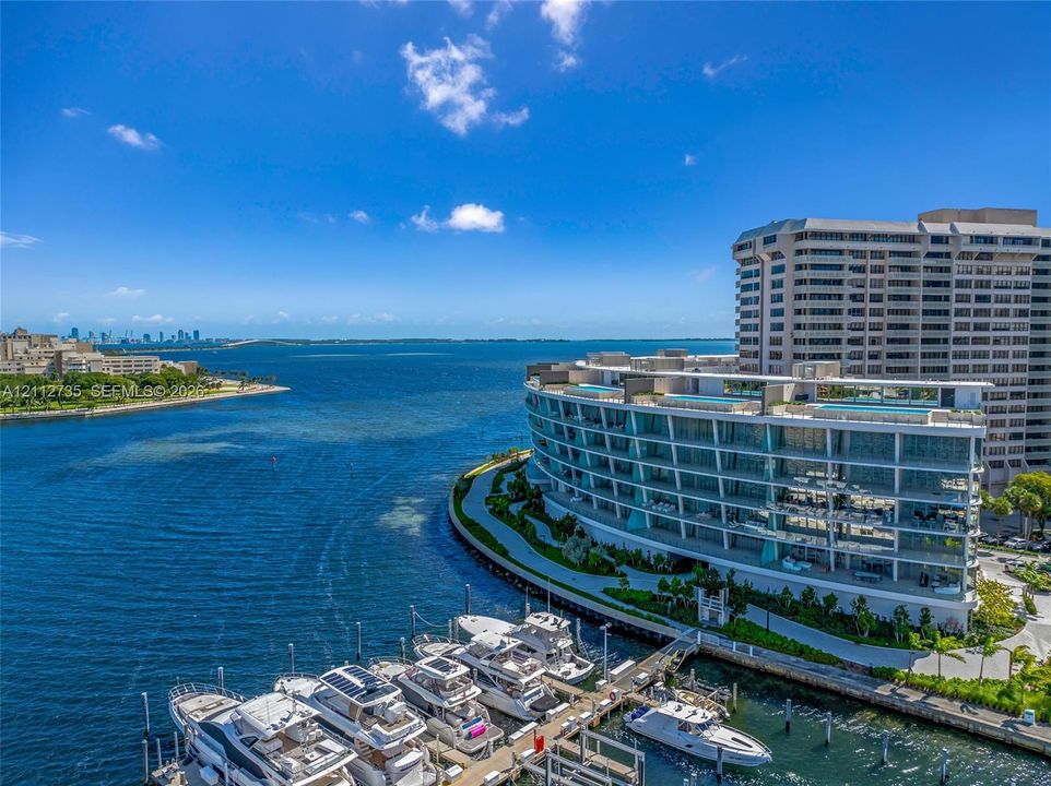 Waterfront mid-rise structure featuring floor-to-ceiling glass paneling, wraparound balconies, and a private deep-water marina