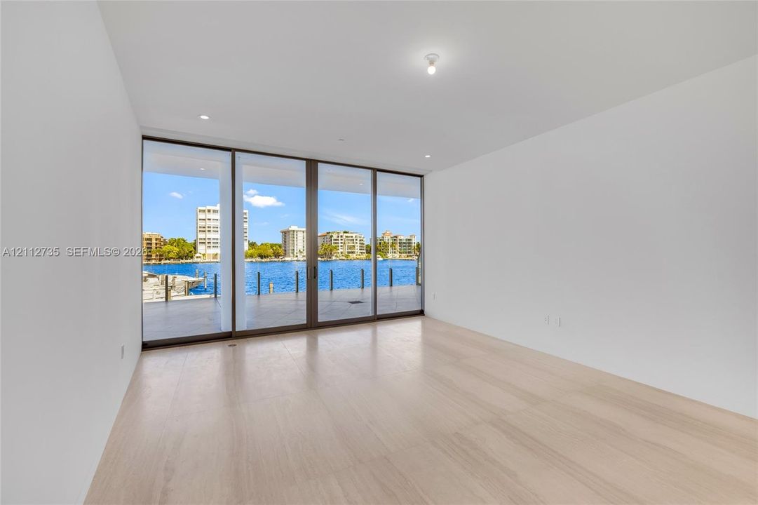 Floor-to-ceiling sliding glass panels with metal framing, wood-finish flooring, and expansive water exposure