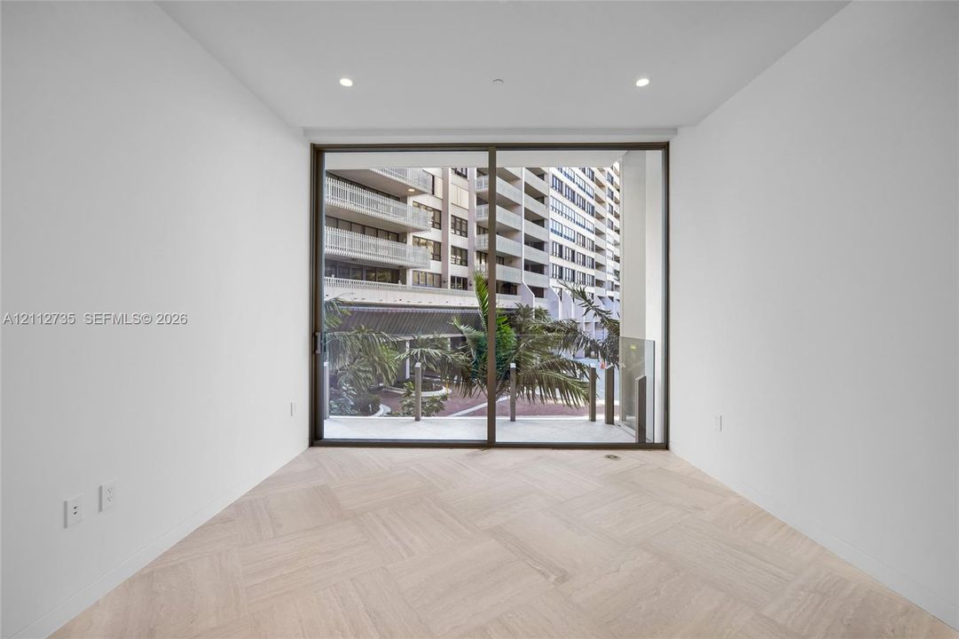 Herringbone wood-finish flooring, floor-to-ceiling sliding glass doors, and recessed lighting