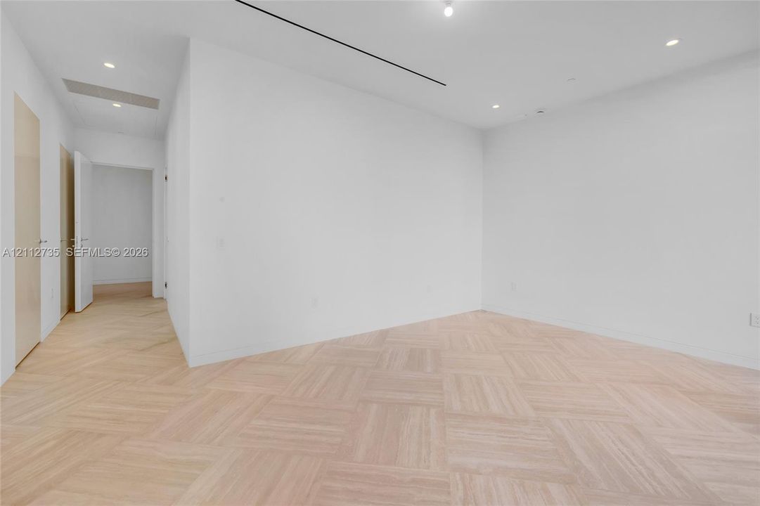 Interior space featuring light-toned wood-finish flooring in a herringbone pattern, recessed lighting, and smooth-finish white walls