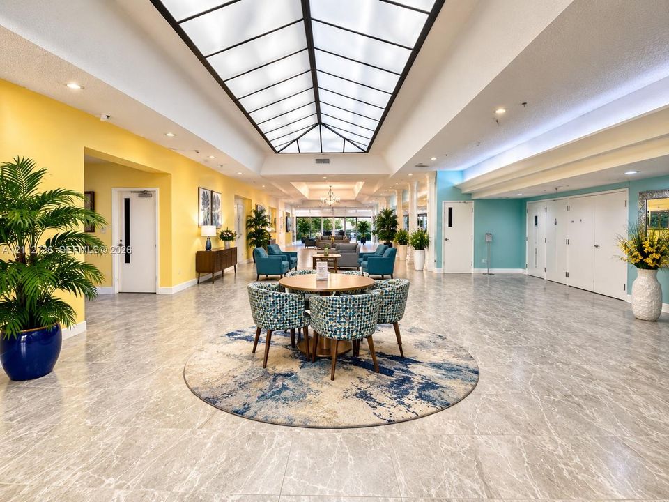 Expansive interior space featuring a large central skylight, high ceilings with recessed lighting, and stone-finish flooring throughout