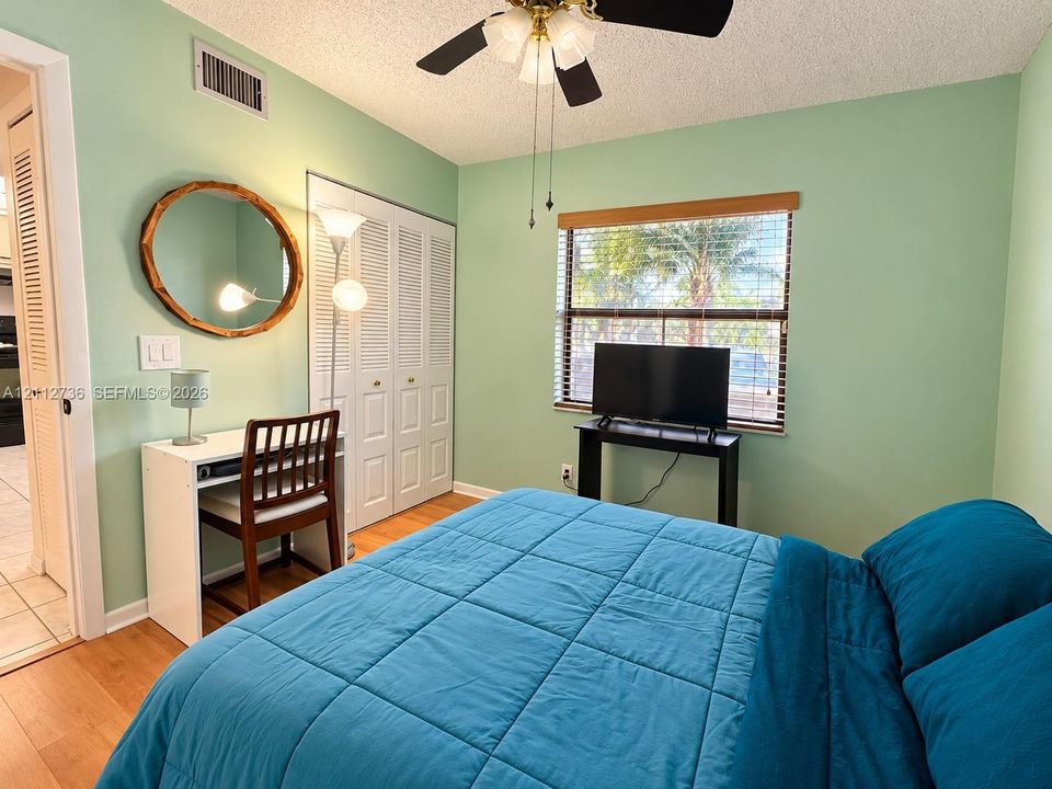 Room featuring wood-finish flooring, a ceiling fan with light fixture, and closet with louvered double doors