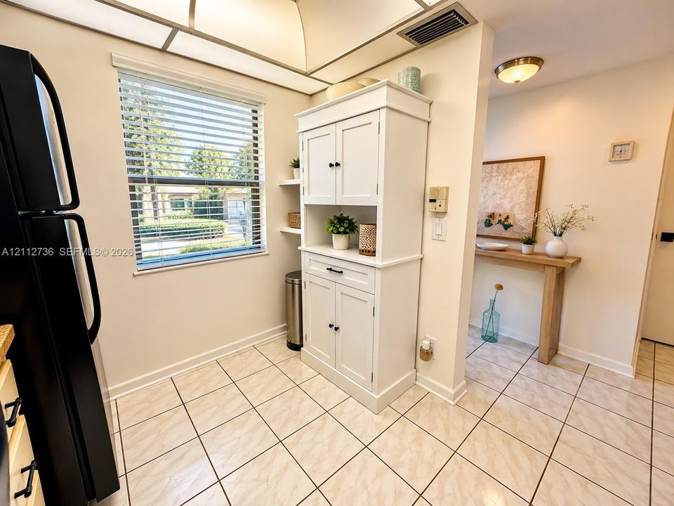 Ceramic tile flooring, built-in white cabinetry with storage drawers, recessed kitchen lighting, and neutral wall tones