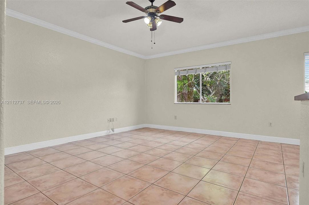 Neutral-toned interior featuring ceramic tile flooring, crown molding, and a multi-light ceiling fan