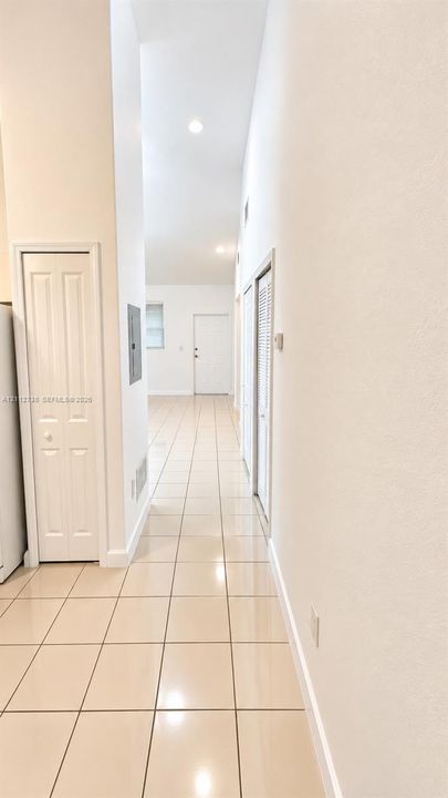 High-ceiling interior featuring neutral ceramic tile flooring, recessed lighting, and white paneled interior doors