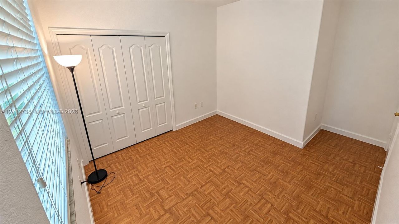 Room featuring parquet wood-finish flooring, white walls, and a four-panel bi-fold closet