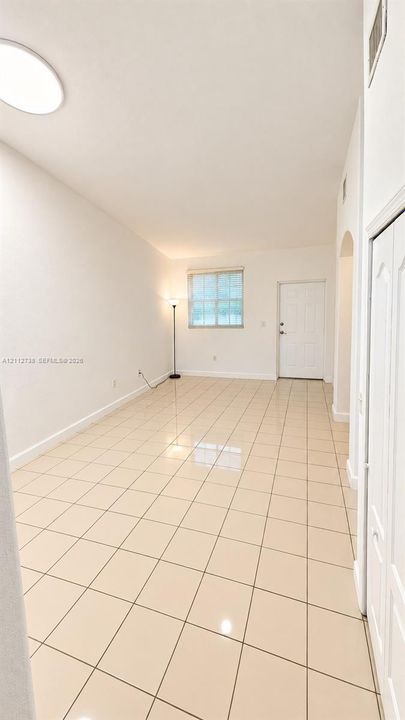 High-ceiling room featuring large-format tile flooring, recessed lighting, and a six-panel entry door