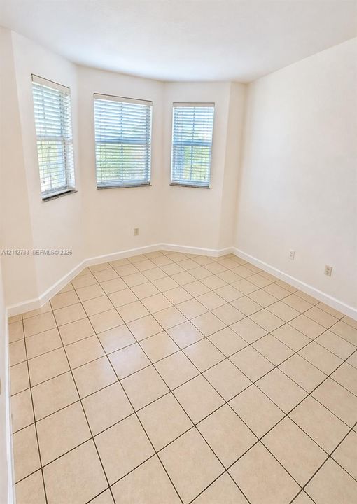 Interior room featuring large format tile flooring and a tripartite bay window configuration with integrated blinds