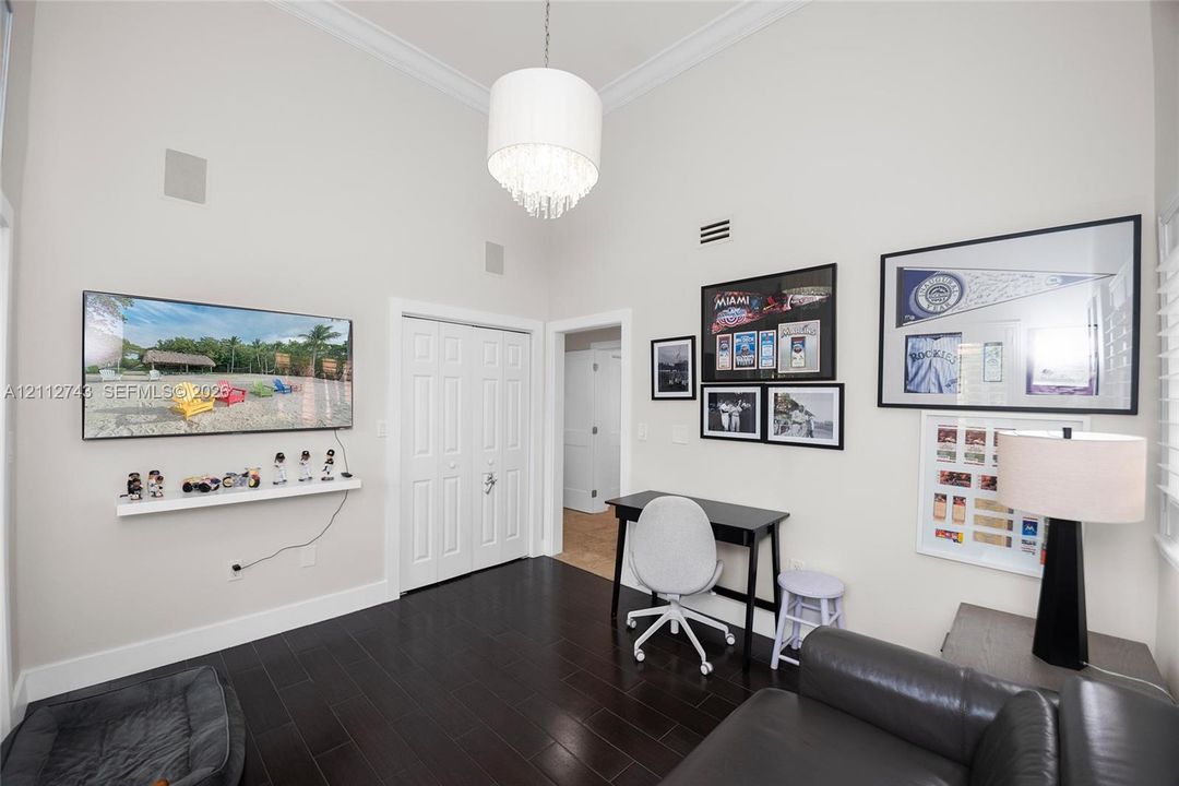 High vaulted ceilings featuring crown molding, dark wood-finish flooring, and a crystal drum chandelier