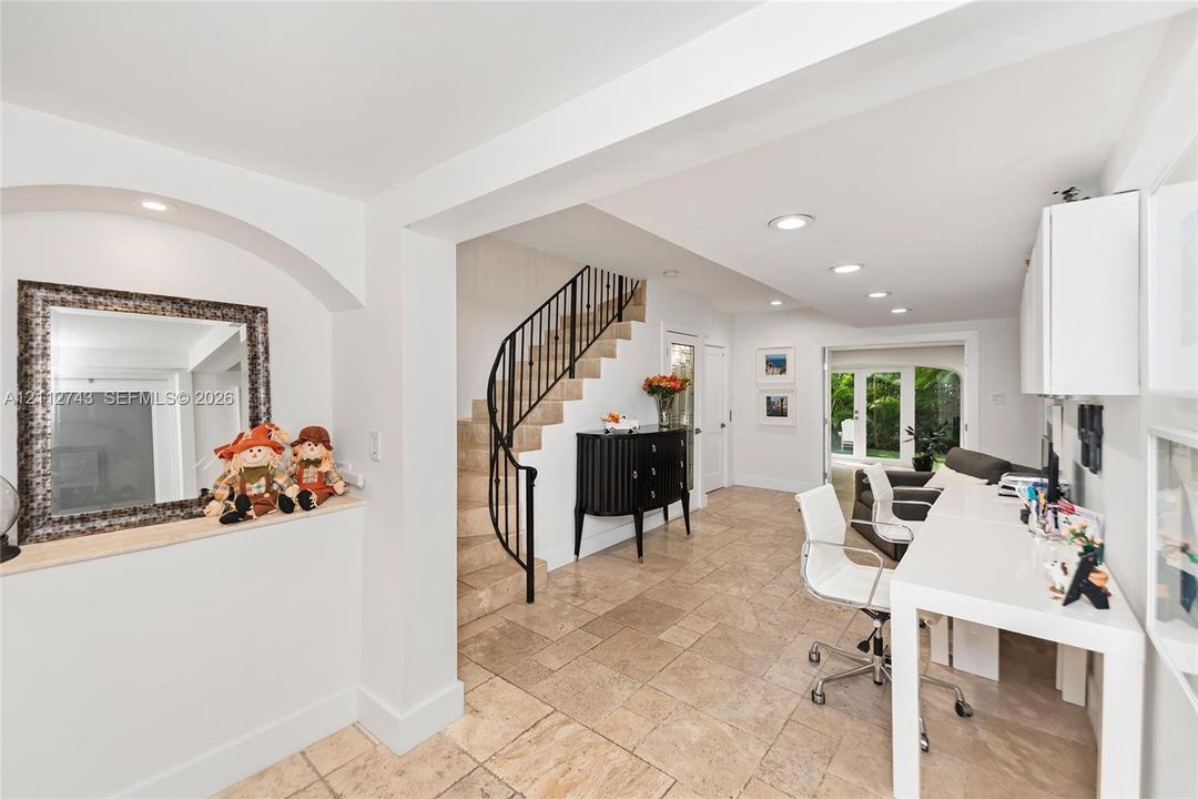 Interior space featuring stone-tile flooring, a curved staircase with metal railing, built-in wall niche with recessed lighting, and recessed ceiling lighting throughout