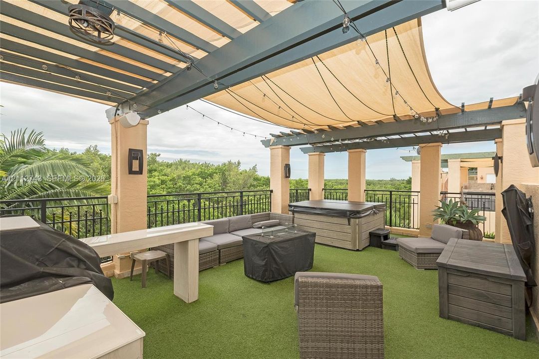 Rooftop terrace featuring a covered pergola, integrated overhead lighting, metal railings, and a built-in outdoor kitchen structure