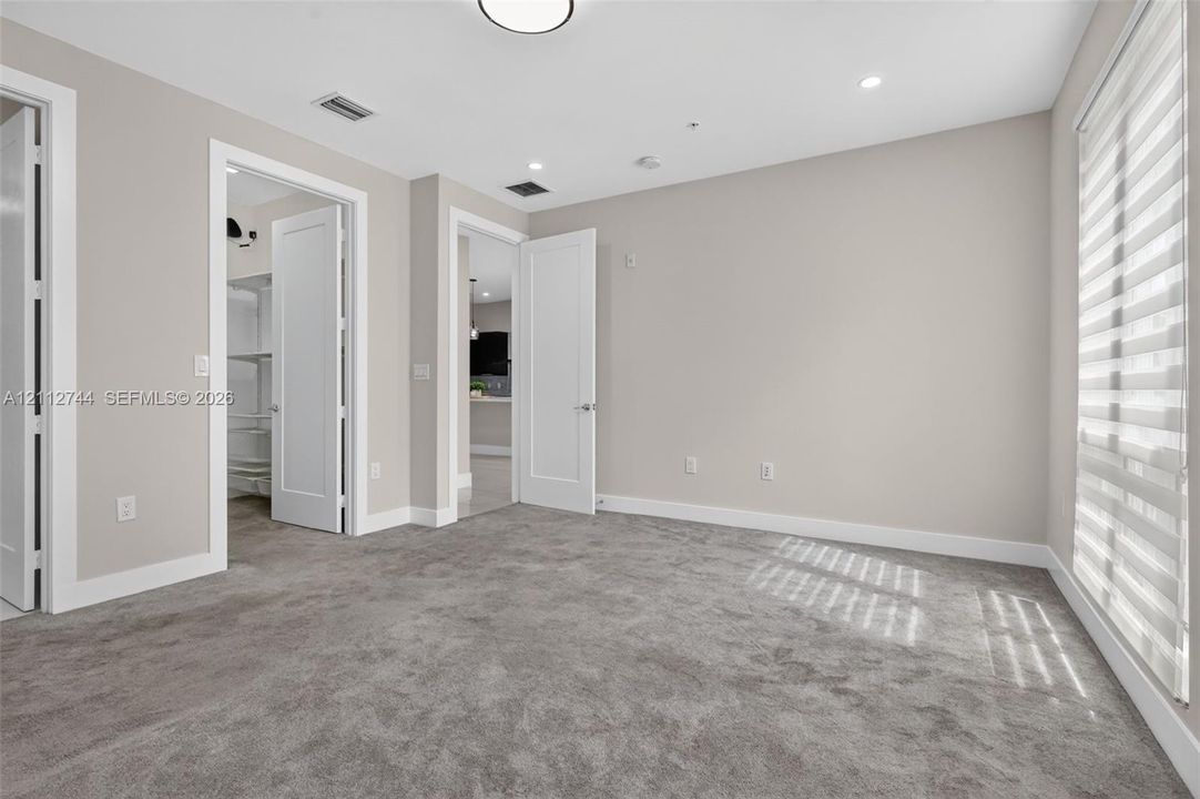Neutral-toned interior featuring wall-to-wall carpeting, shaker-style doors, recessed lighting, and tiered window shades