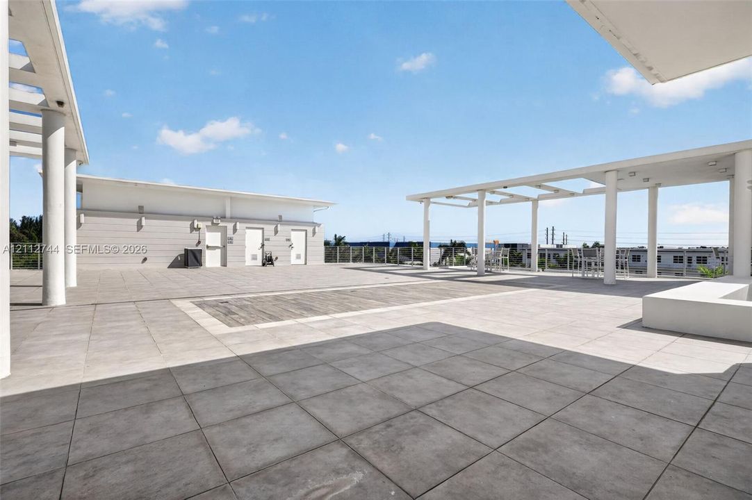Expansive rooftop terrace featuring large-format stone tile flooring, structural pergolas, and a perimeter railing