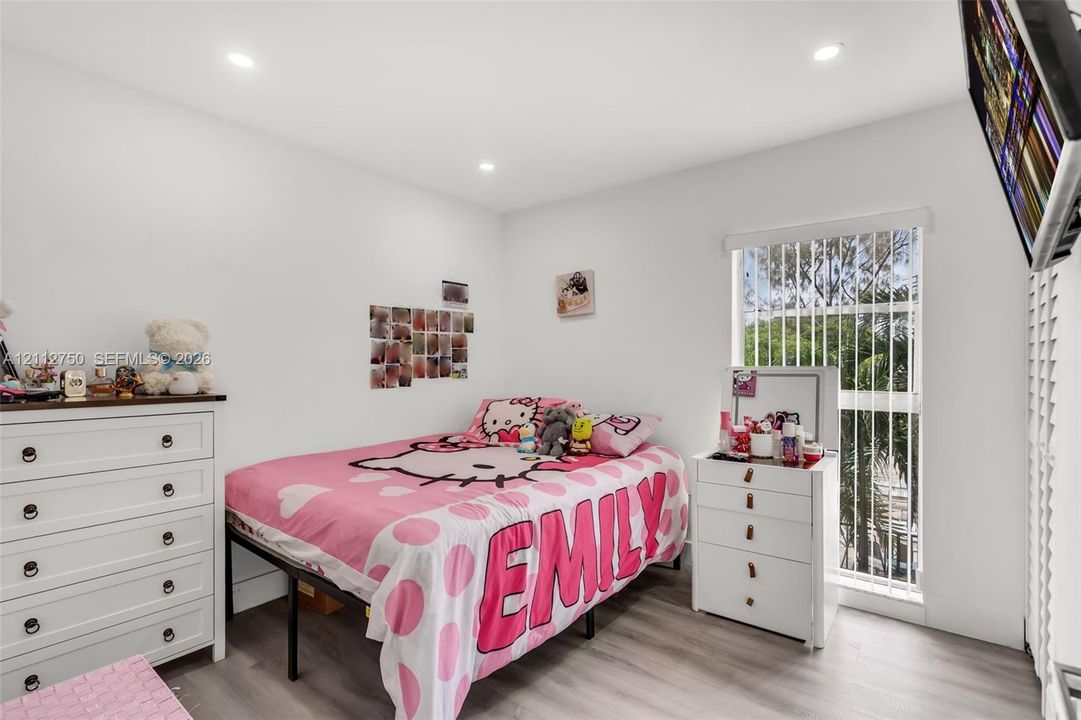 Bright room featuring wood-finish flooring, recessed lighting, and a floor-to-ceiling window with vertical blinds
