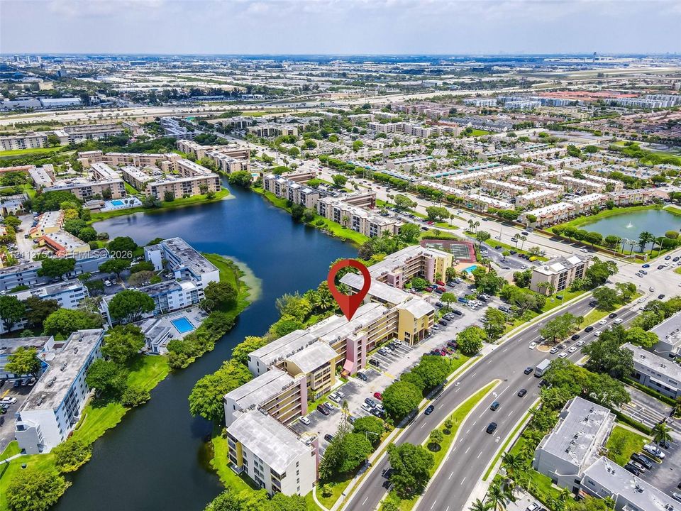 Aerial perspective of a multi-story residential building featuring water frontage and on-site parking