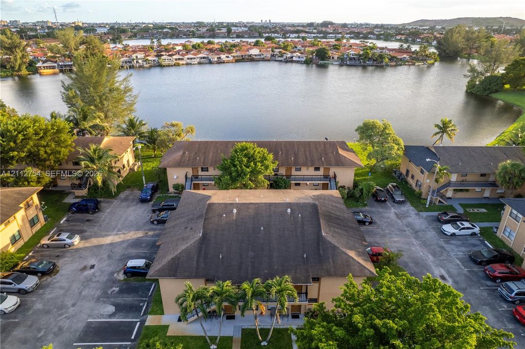 Aerial perspective of multi-family residences featuring lakefront positioning, mature palms, and surface parking