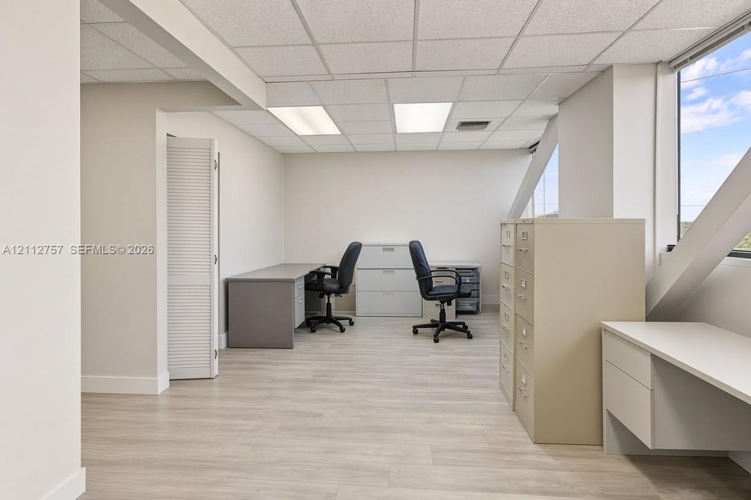 Interior space featuring wood-finish flooring, a suspended acoustic ceiling with recessed lighting, angled wall detailing, and a bi-fold closet door