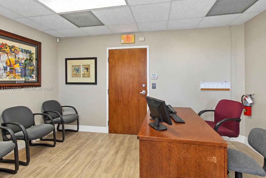 Interior space featuring wood-finish flooring, a solid wood-core door, and a drop ceiling with recessed lighting