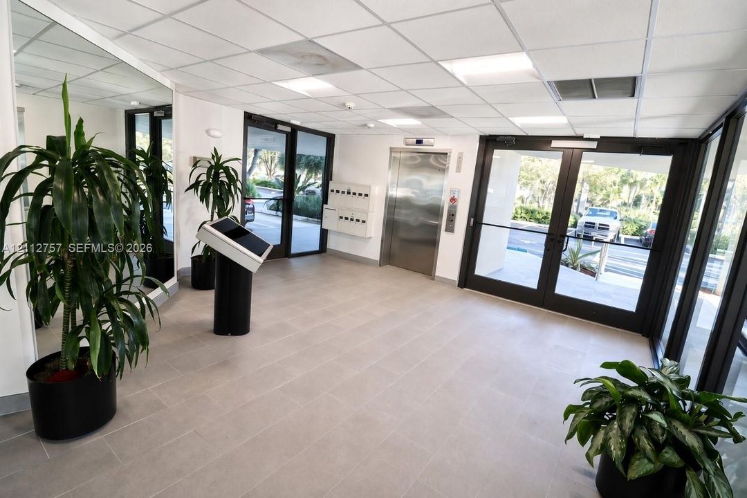 Building lobby featuring tile flooring, a stainless steel elevator, recessed lighting, and expansive glass-paneled double entry doors