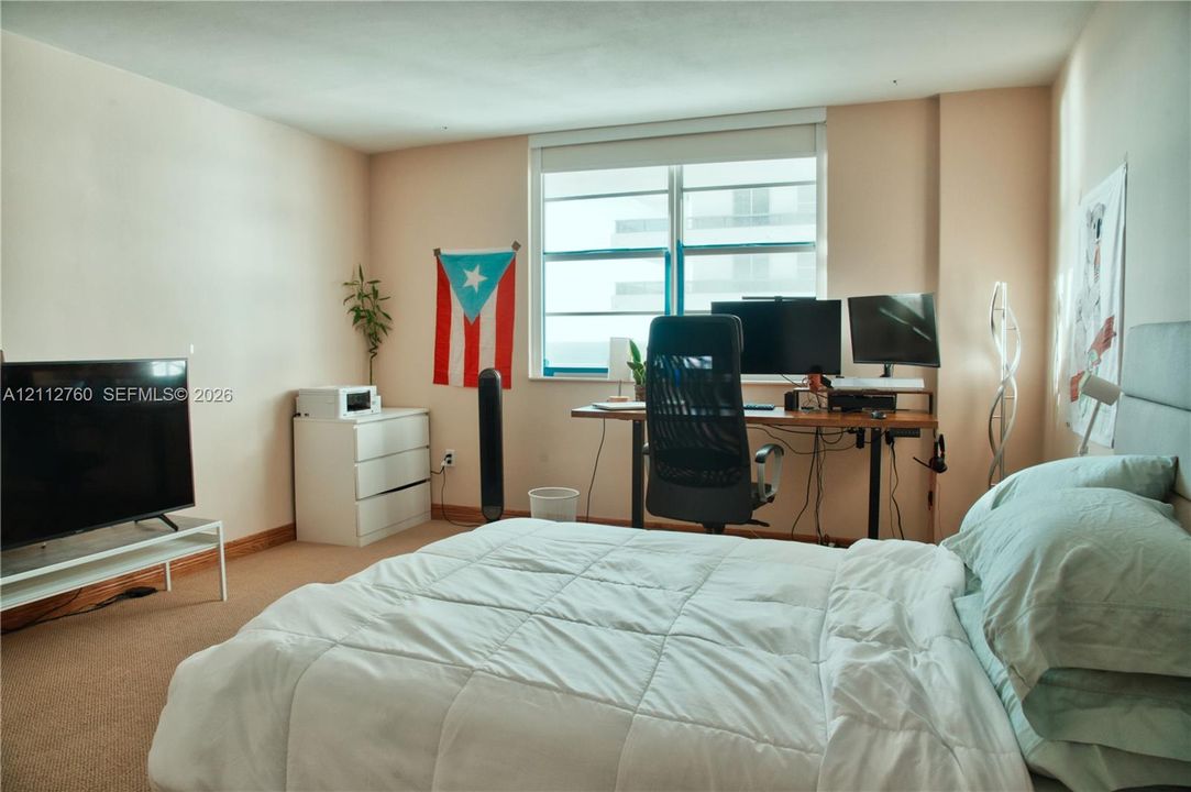 Bedroom featuring wall-to-wall carpeting and a multi-pane horizontal window with integrated roller shade