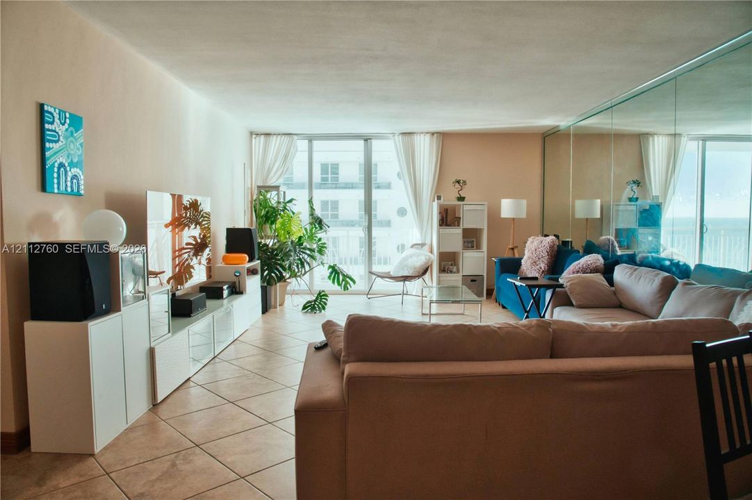 Ceramic tile flooring, full-wall mirrored accent, and sliding glass doors providing outdoor access