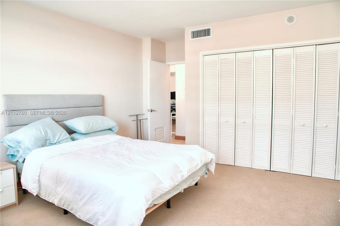 Wall-to-wall carpeting, expansive floor-to-ceiling closets with white louvered bi-fold doors, and neutral wall tones