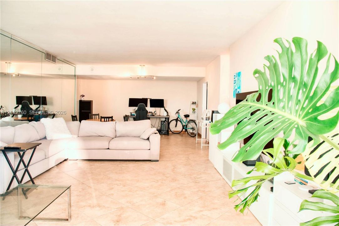 Open floor plan featuring large-format ceramic tile flooring and floor-to-ceiling mirror wall paneling