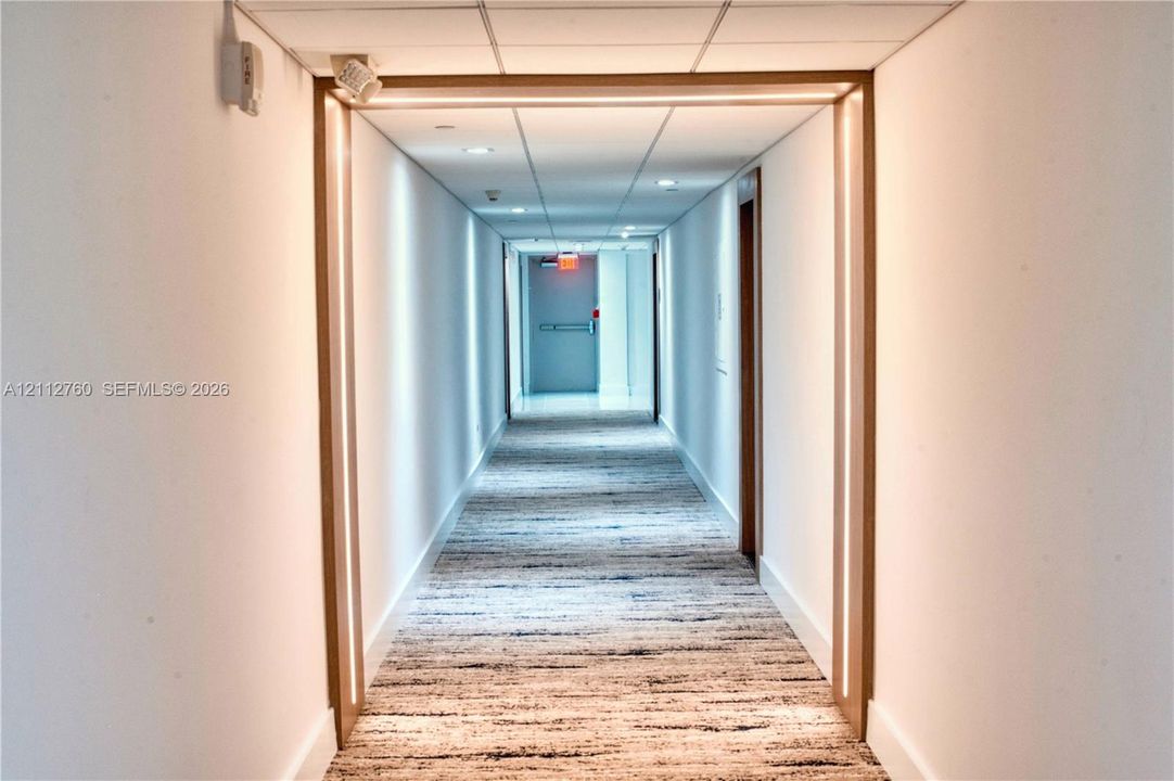 Hallway featuring integrated linear LED lighting, wood-trim portal framing, recessed ceiling lighting, and textured carpeting