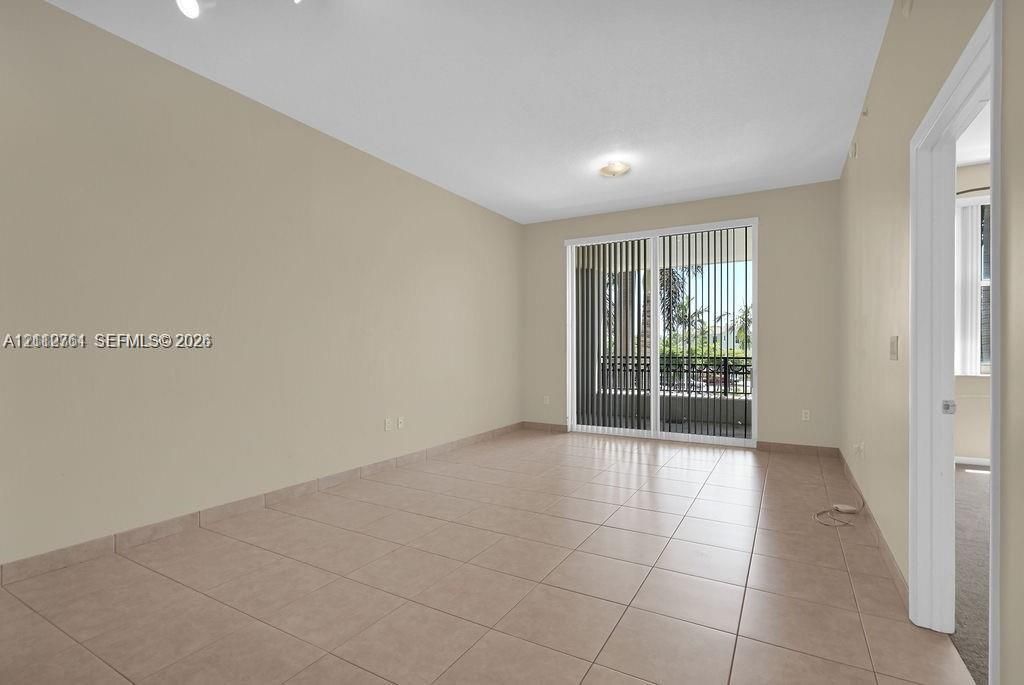 Interior space featuring neutral-toned wall paint, ceramic tile flooring, and a sliding glass door with vertical blinds providing exterior access