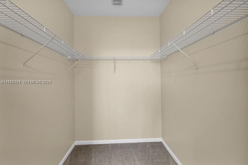 Storage closet featuring neutral wall paint, gray carpeting, and white wire shelving