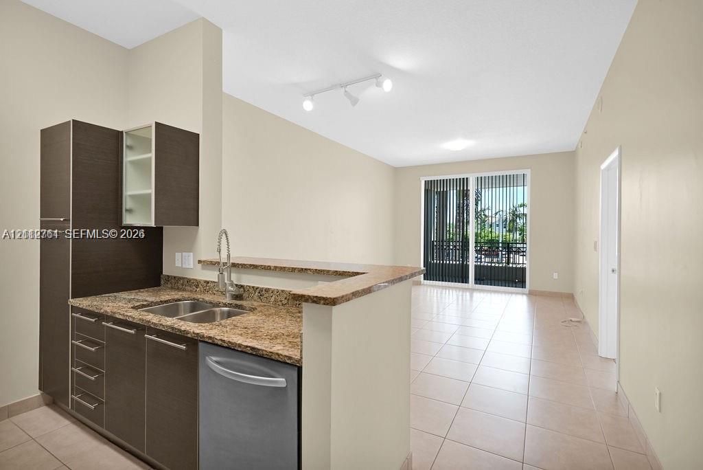 Kitchen featuring dark cabinetry, stone-finish countertops, stainless steel dual-basin sink, and ceramic tile flooring throughout