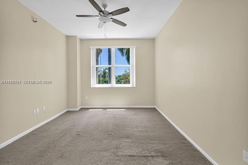 Room featuring neutral-toned carpeting, a multi-blade ceiling fan with integrated lighting, and a dual-pane window