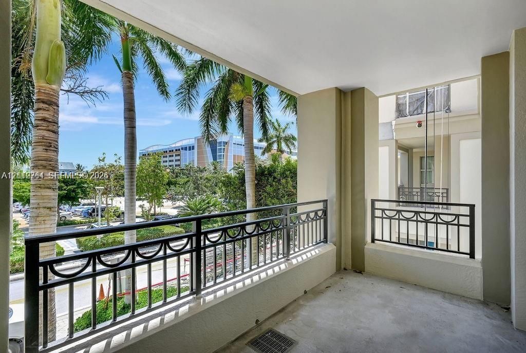 Covered balcony featuring concrete flooring and decorative metal railings