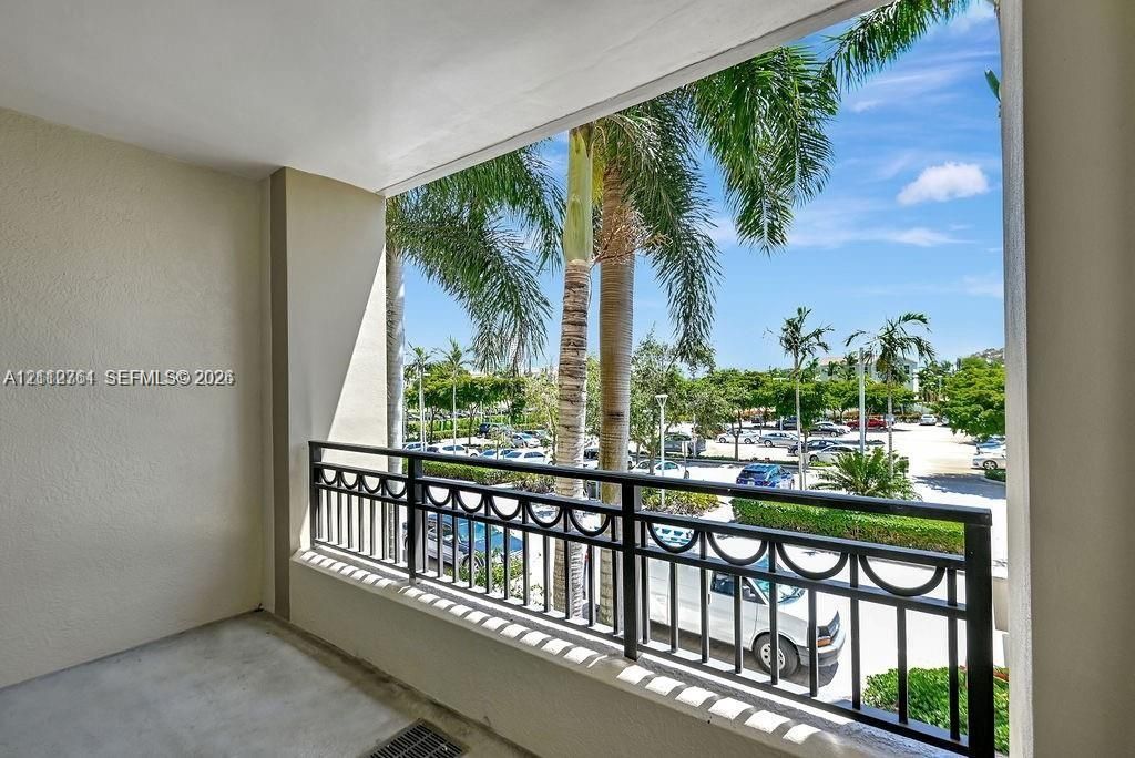 Covered balcony featuring concrete flooring and a decorative black metal railing