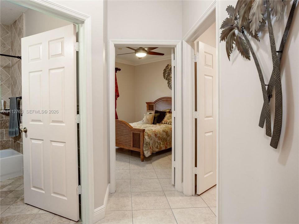 Interior hallway featuring six-panel interior doors, light-colored tile flooring, and a ceiling fan with integrated lighting