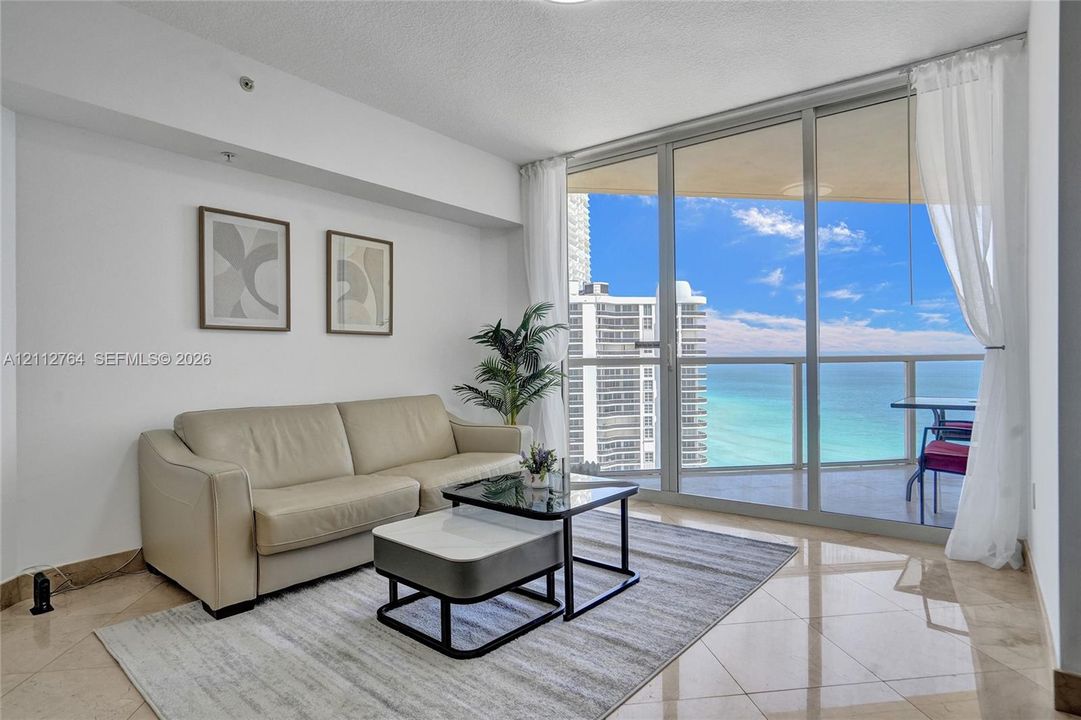 Floor-to-ceiling sliding glass doors, private balcony, polished stone tile flooring, and neutral wall finish