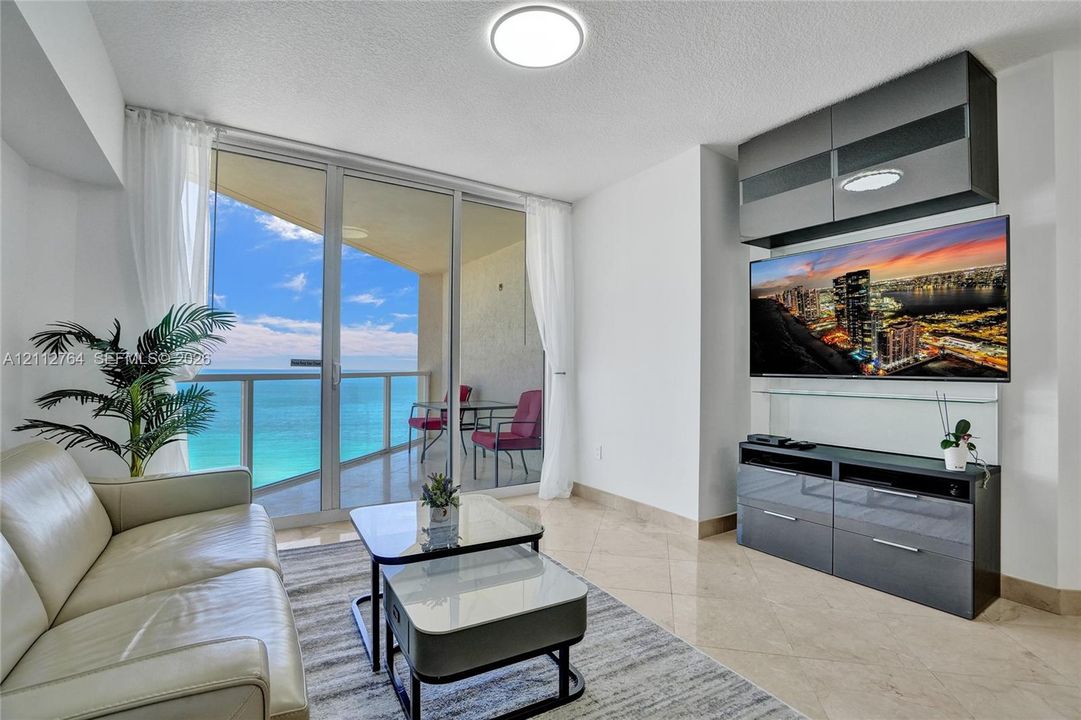 Floor-to-ceiling glass doors, expansive private balcony, polished stone flooring, and built-in high-gloss cabinetry