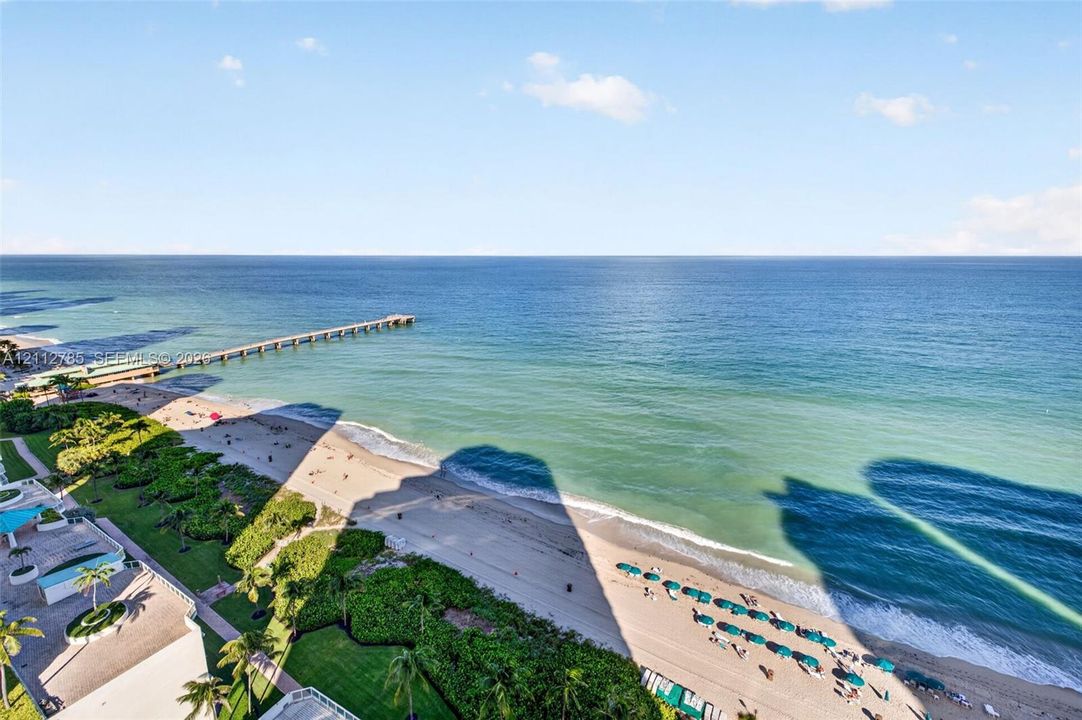 Panoramic oceanfront exposure featuring an expansive coastal horizon, sandy beach shoreline, and a prominent pier structure