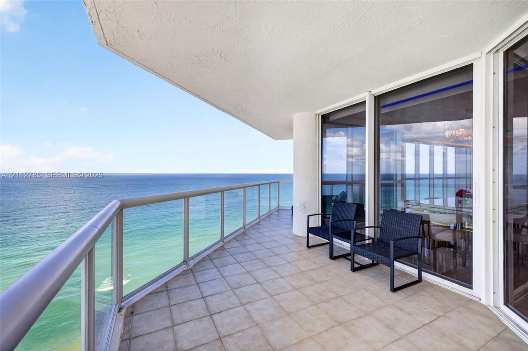 Covered balcony featuring tile flooring, aluminum railing, and floor-to-ceiling glass paneling overlooking the ocean