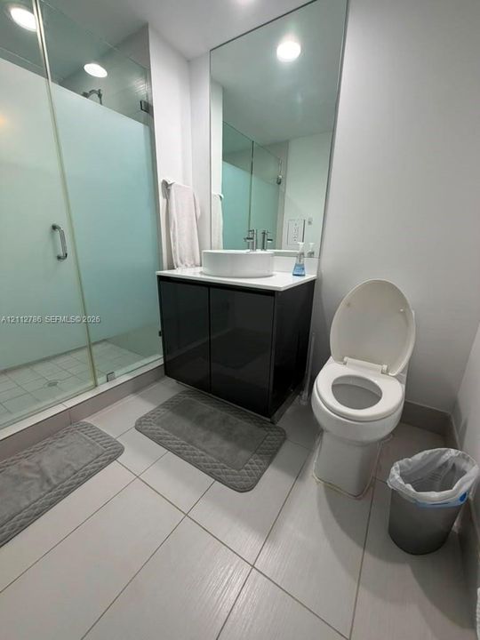 Bathroom featuring a glass-enclosed shower with frosted paneling, vanity with a rectangular vessel sink, polished countertop, and full-height vanity mirror