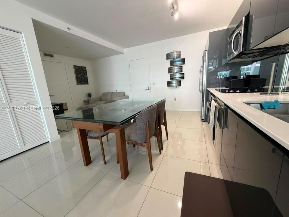 High-gloss cabinetry, stone countertops, integrated stainless steel appliances, and large-format tile flooring