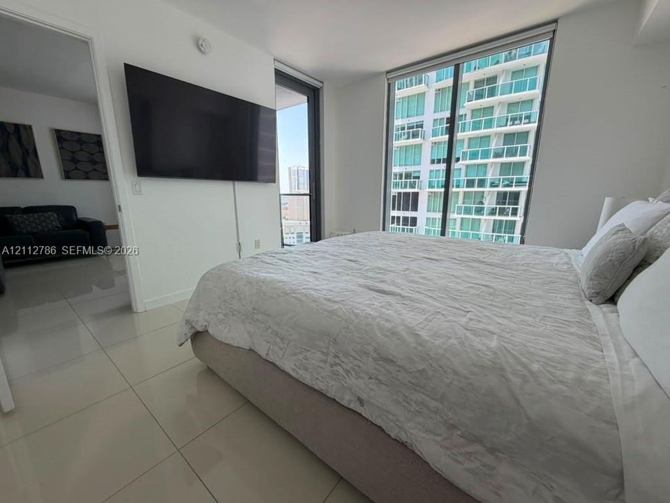 Floor-to-ceiling windows with expansive glass panels, large-format tile flooring, and integrated door access to an exterior balcony