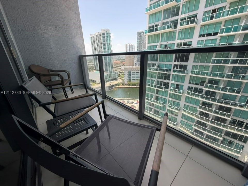 Private balcony featuring large-format tile flooring and a glass-paneled railing