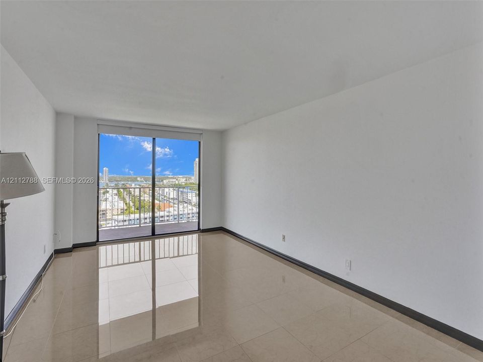 Large-format tile flooring, expansive sliding glass doors, and a private balcony featuring a metal railing