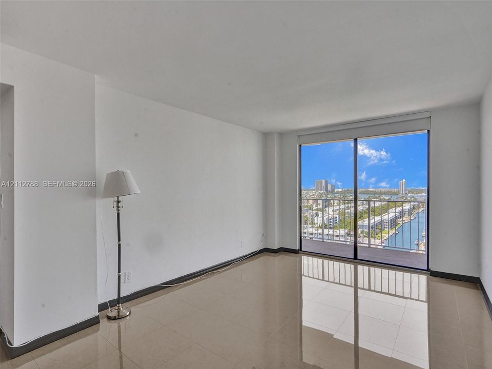 Interior space featuring large-format tile flooring, floor-to-ceiling glass sliding doors, and a private balcony with metal railing