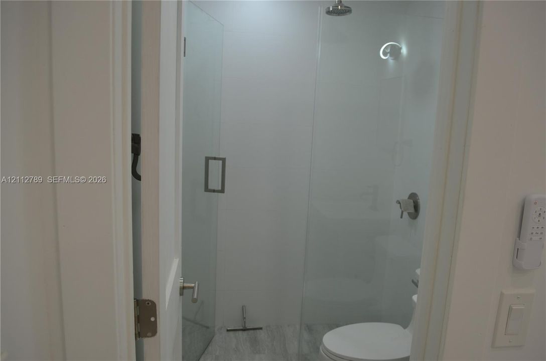 Walk-in shower featuring a glass enclosure, rainfall showerhead, and tile flooring