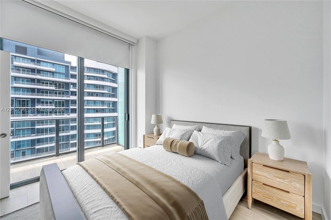 Floor-to-ceiling glass sliding door, integrated roller shade, neutral wall palette, and wood-finish flooring