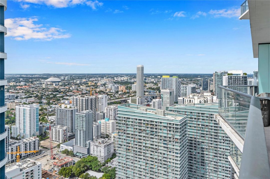 Elevated balcony featuring a glass panel railing and panoramic urban skyline exposure