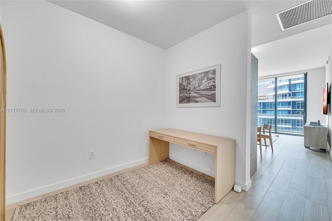 Interior space featuring light-toned wood-finish flooring and floor-to-ceiling windows with expansive exterior building visibility