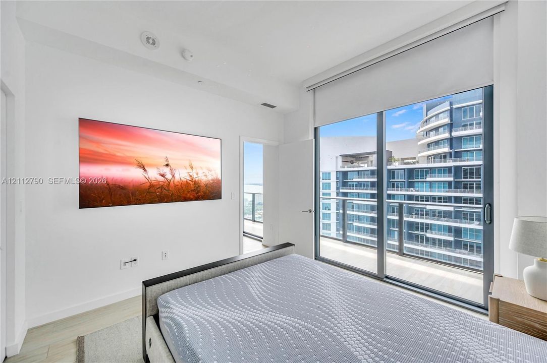 Floor-to-ceiling sliding glass door, integrated roller shade, recessed ceiling lighting, and light-toned flooring